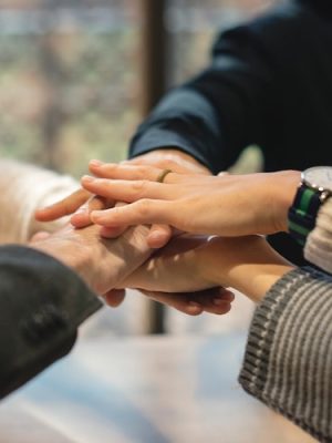 Close-up of multiple hands stacked together, symbolising teamwork and collaboration
