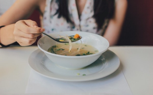 Lady eating vegetable-dense soup dish